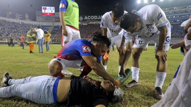 Jugadores de Alianza y FAS socorren a una aficionada afectada por la estampida